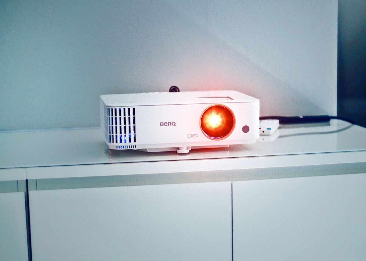 Detalhe de uma lente de projetor de cinema emitindo luz.