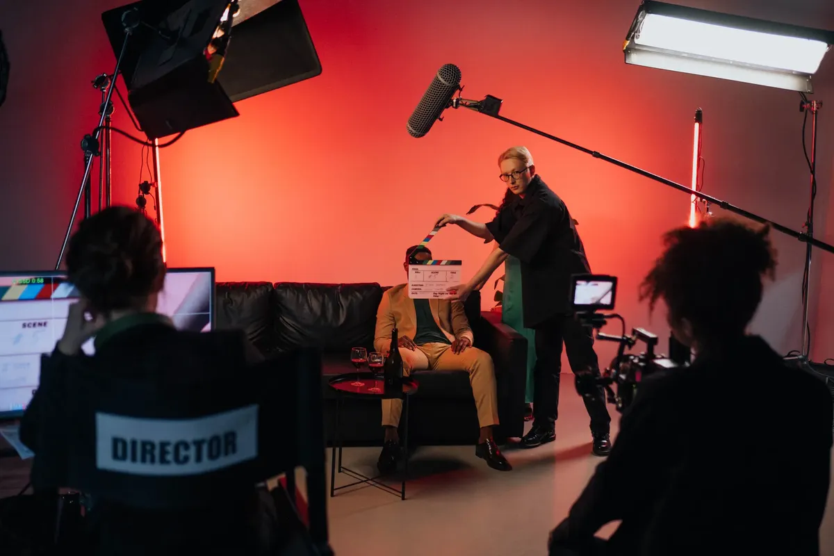 A behind-the-scenes look at a filming crew setting up a scene indoors with lighting equipment.