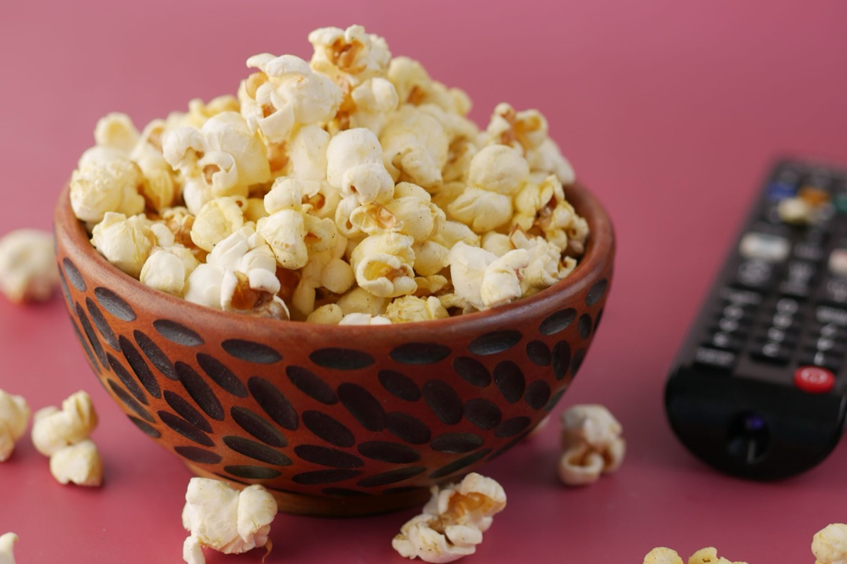 televisie afstandsbediening en popcorn op een bank